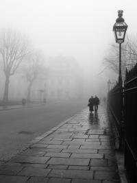 Couple walking down a misty street lined with lampposts